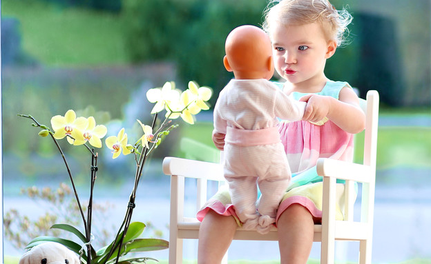 שיער קצר ילדה עם בובה יושבת על כסא (צילום: Shutterstock)