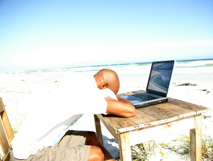 אדם יושב בים מול שולחן עם לפטופ (צילום: jupiter images)