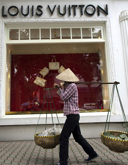 אישה וייטנאמית הולכת מול חנות של לואי ויטון בהאנוי (צילום: Paula Bronstein, GettyImages IL)