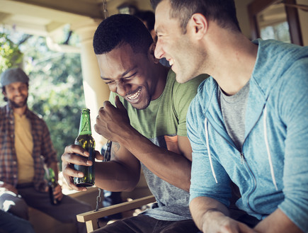 חברים יושבים צוחקים ושותים בירה (צילום: MintImages, Shutterstock)