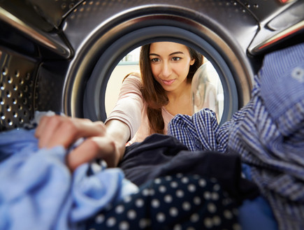 אישה מוציאה בגדים ממייבש כביסה (אילוסטרציה: Monkey Business Images, Shutterstock)