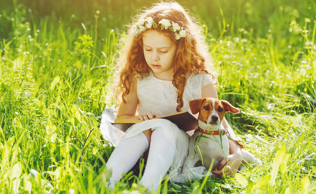 ילדה קוראת ספר עם כלב (צילום: Yuliya Evstratenko, Shutterstock)