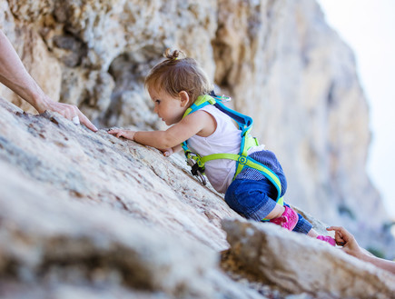 תינוקת עם רתמה מטפסת על צוק (צילום: Photobac, Shutterstock)