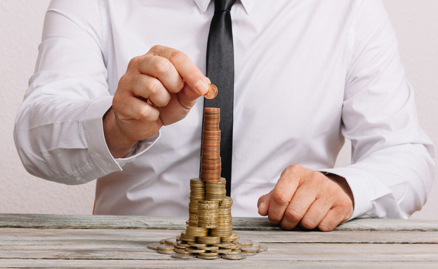 חיסכון- איש עסקים בונה מגדל של מטבעות (צילום: MichaelJayBerlin, Shutterstock)