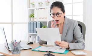 אישה מופתעת קוראת מסמכים (אילוסטרציה: PR Image Factory, Shutterstock)