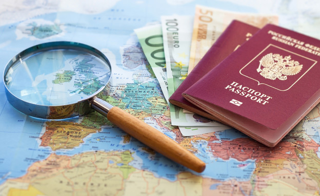 דרכונים עם שטרות כסף על מפת העולם (צילום: By Dafna A.meron)