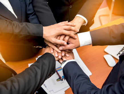 אנשי עסקים שמים ידיים כדי להפגין אחדות (צילום: יחסי ציבור, shutterstock)