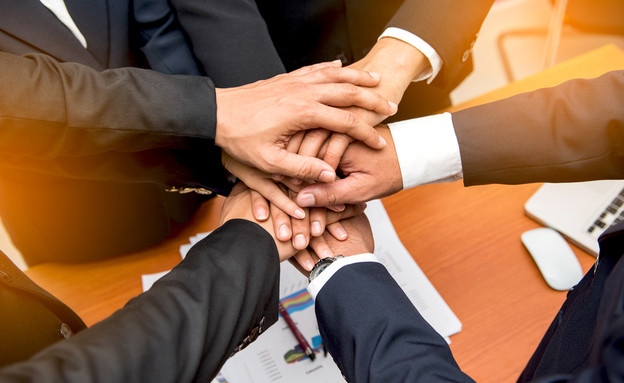 אנשי עסקים שמים ידיים כדי להפגין אחדות (צילום: יחסי ציבור, shutterstock)