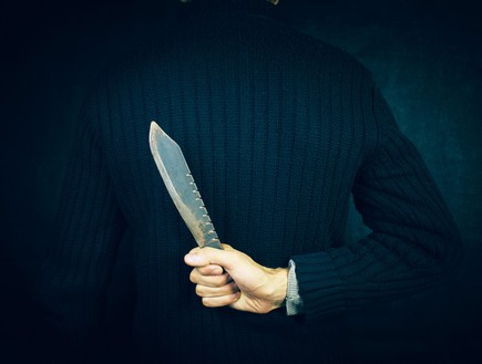 אדם בחליפה מחזיק סכין מאחורי הגב (צילום: Sasun Bughdaryan, ShutterStock)