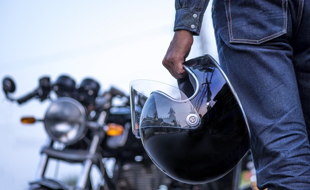 אופנוען מחזיק קסדה (צילום: Virojt Changyencham, ShutterStock)