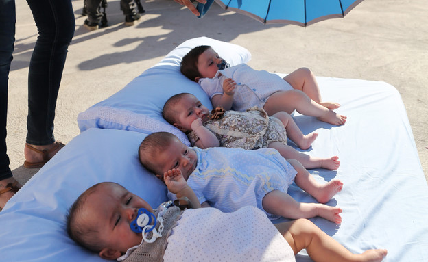 תינוקות ומטריה (צילום: GettyImages-CESAR MANSO AFP)