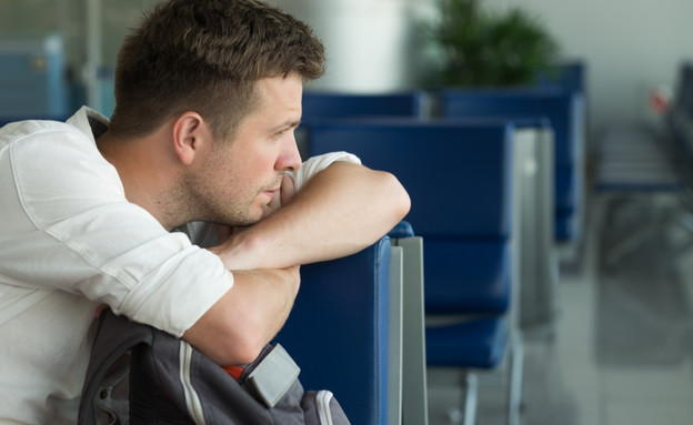 גבר עצוב בשדה התעופה (צילום: Koldunova Anna, ShutterStock)
