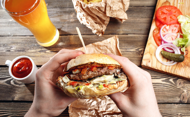 ידיים מחזיקות המבורגר (צילום: shutterstock)