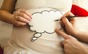 גבר כותב על פיסת נייר שמונחת על בטן של אישה בהריון (אילוסטרציה: By Dafna A.meron, shutterstock)