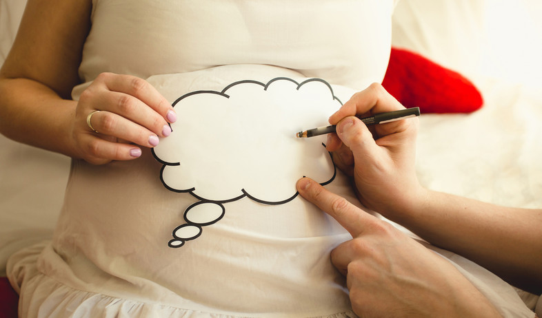 גבר כותב על פיסת נייר שמונחת על בטן של אישה בהריון (אילוסטרציה: By Dafna A.meron, shutterstock)