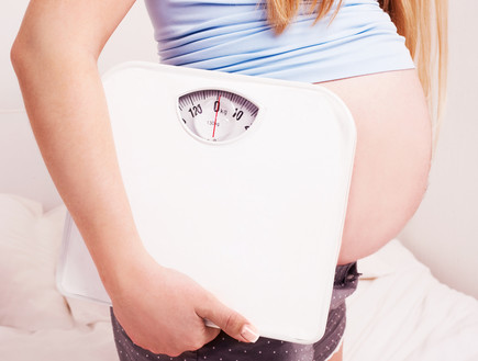 אישה בהריון מחזיקה משקל (אילוסטרציה: By Dafna A.meron, shutterstock)