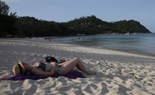 אישה משתזפת על חוף בקופנגן (צילום: Paula Bronstein, Getty Images)