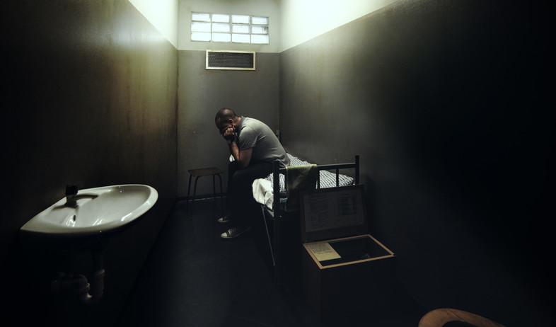 אסיר יושב בכלא (צילום: By Peppinuzzo, ShutterStock)