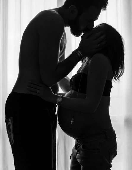 גבר מנשק אישה בהיריון (צילום: andrea bertozzini, unsplash)