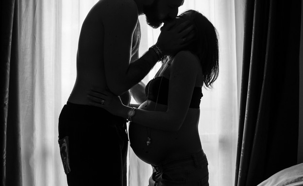 גבר מנשק אישה בהיריון (צילום: andrea bertozzini, unsplash)