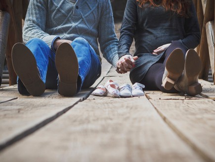 זוג מחזיק ידיים כשמולם נעלי ילדים (אילוסטרציה: unsplash)