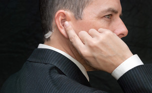 סוכן חשאי שם אצבע על אוזניה באוזן - אילוסטרציה (צילום: David Stuart Productions, ShutterStock)