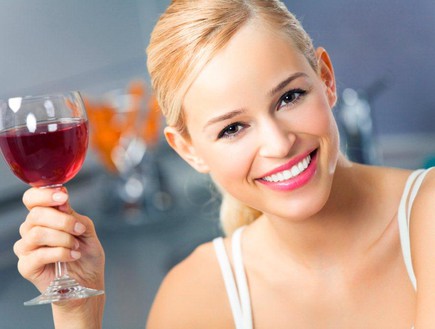 אישה מחייכת מחזיקה כוס יין (צילום: אימג'בנק/Thinkstock)