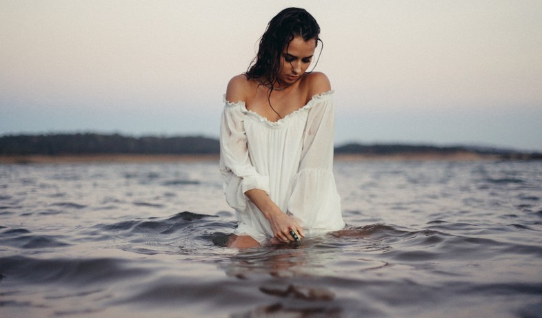 אישה עומדת בתוך אגם (אילוסטרציה: ryan moreno, unsplash)