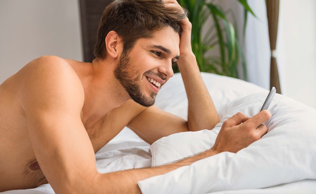 גבר במיטה עם הטלפון (צילום: Olena Yakobchuk, Shutterstock)