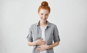 אישה שמחה מחזיקה את הבטן (צילום: WAYHOME studio, shutterstock)