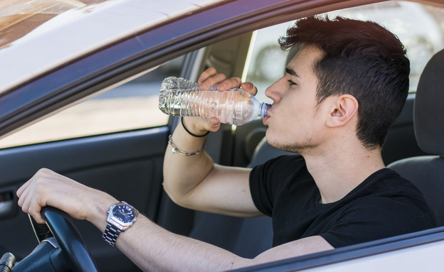איש שותה תוך כדי נהיגה (צילום: ArtOfPhotos, shutterstock)