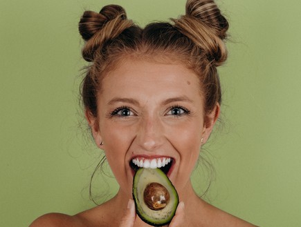 אישה אוכלת אבוקדו (צילום: noah-buscher-unsplash)