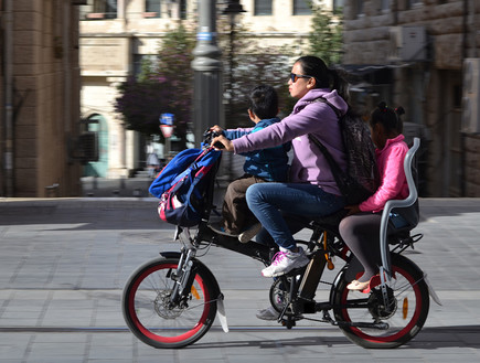 אמא ושני ילדים רוכבים על אופניים חשמליים בירושלים (צילום: By Dafna A.meron, shutterstock)