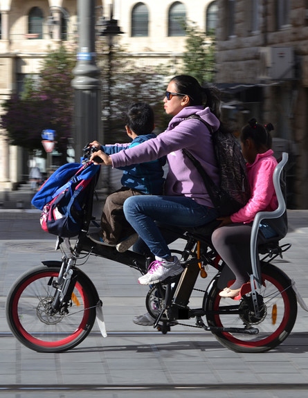 אמא ושני ילדים רוכבים על אופניים חשמליים בירושלים (צילום: By Dafna A.meron, shutterstock)
