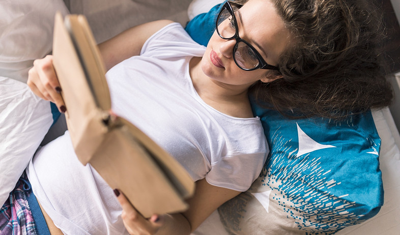 אישה קוראת ספר במיטה (אילוסטרציה: Shutterstock)