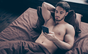 גבר מסמס במיטה (צילום: Roman Samborskyi, shutterstock)