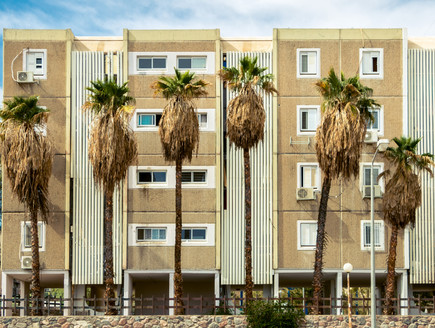 Facade of four storey house on columns with palm tree (צילום: By Dafna A.meron)