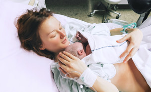 אמא מחזיקה תינוק אחרי לידה בבית החולים (צילום: By Dafna A.meron, shutterstock)