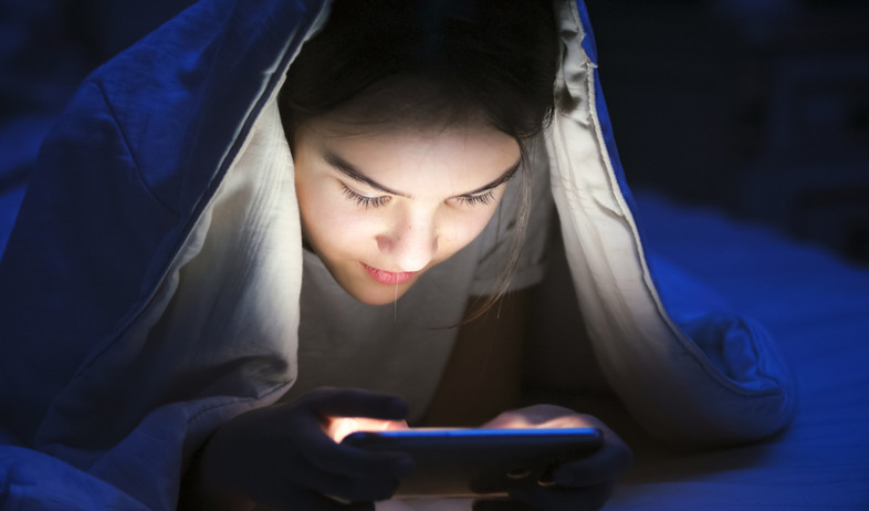ילדה מתחת לשמיכה עם טלפון סלולרי (אילוסטרציה: By Dafna A.meron, shutterstock)