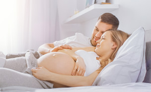 אישה בהיריון עם בן זוגה במיטה (אילוסטרציה: Gorodenkoff, shutterstock)