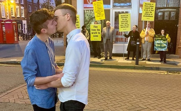 הזוג הגאה שהתנשק מול מפגינים הומופובים (צילום:  Photo by Flash90, פייסבוק. צילום: שימוש לפי סעיף 27א' לחוק זכויות יוצרים)