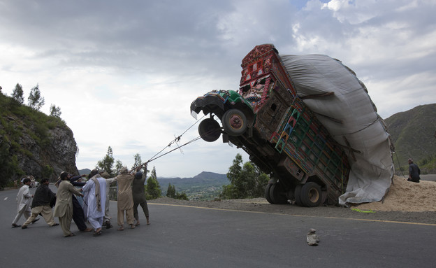 גברים מיישרים בחבל משאית שהתהפכה בפקיסטן (צילום: Mian Kursheed, reuters)