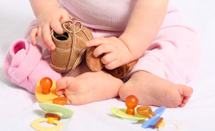 תינוק מחזיק נעליים ולידו מוצצים (צילום: istockphoto)