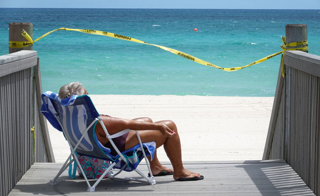 אישה משתזפת בטיילת מול חוף שנסגר בפלורידה (צילום: Joe Raedle, Getty Images)
