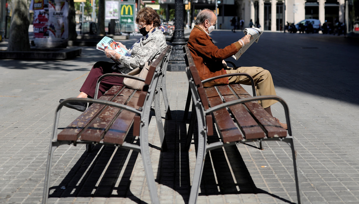 זוג מבוגרים קוראים עיתון עם מסיכות הגנה, ברצלונה