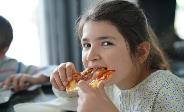 ילדה אוכלת פיצה (צילום: shutterstock_goodluz)