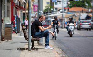 אדם לובש מסיכת פנים על ספסל ומסתכל בסמארטפון בתל אביב (צילום: S. Edelweiss, shutterstock)