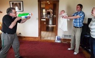כומר מטביל תינוק באמצעות רובה מים