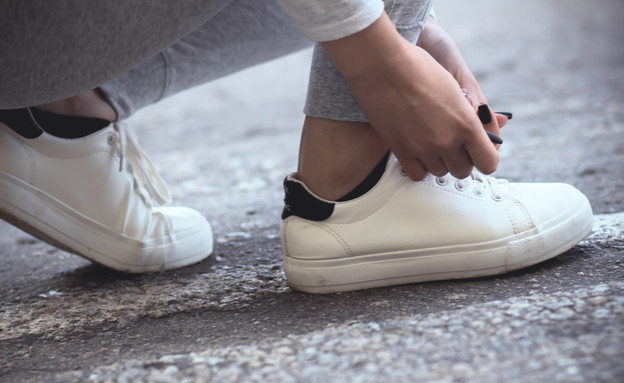 אישה קושרת שרוכי נעליים (צילום: fantom_rd, Shutterstock)