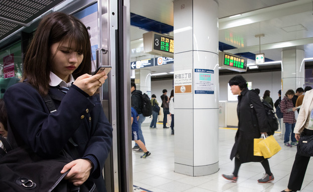 יפן, בחורה מסתכלת על פלאפון (צילום: נתי שוחט, פלאש 90)